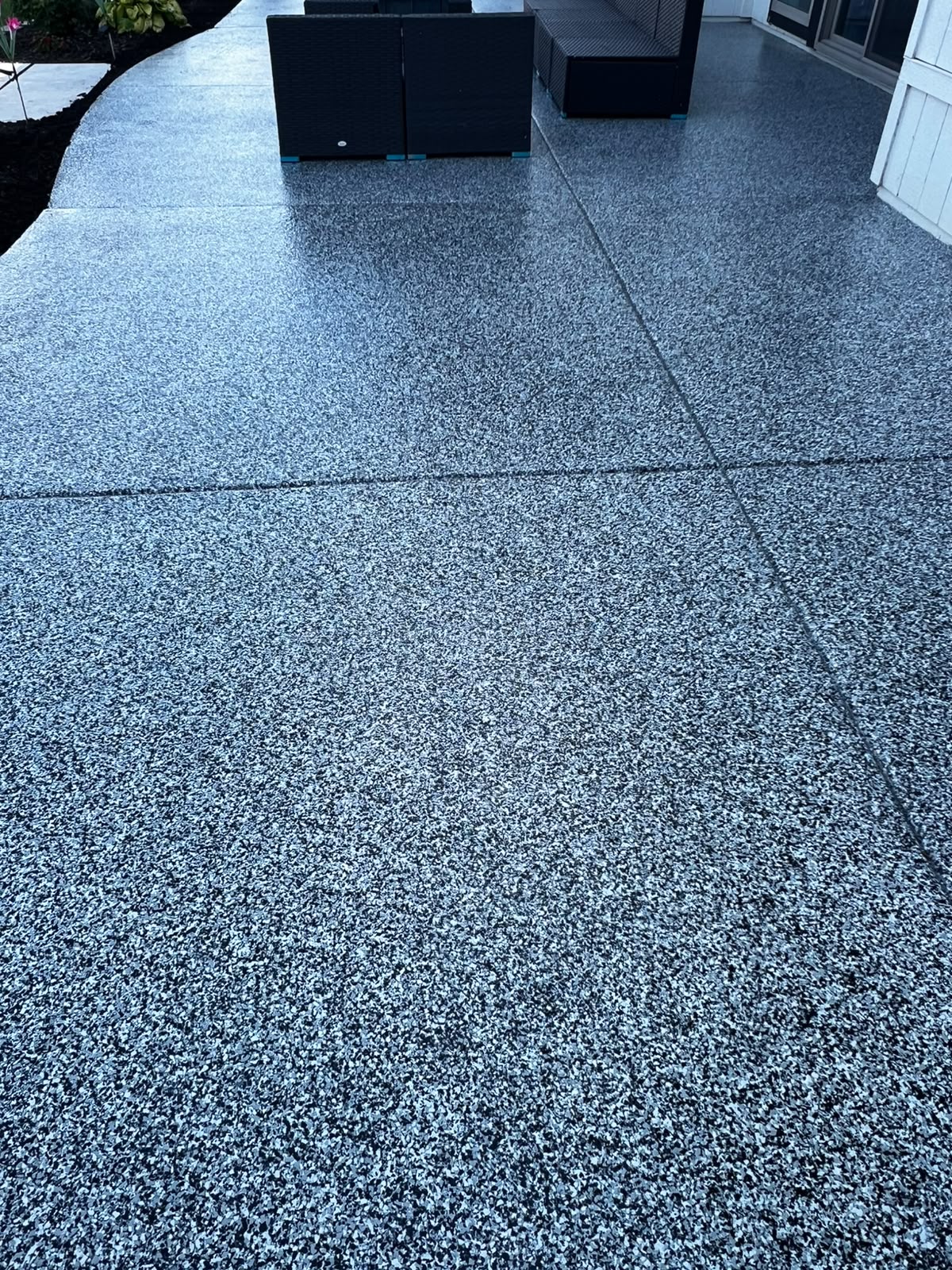 High-angle view of a speckled patio floor coating with outdoor furniture in the background